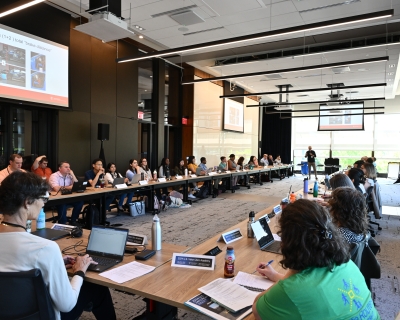 People sitting around a table looking over at a presenter.