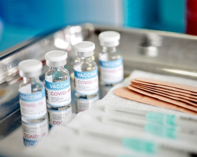 covid vaccine vials, syringes, and bandaids on a metal tray