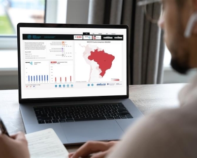 A computer screen featuring data, including a lrge red map of Brazil. A blurry image of a man is on the right-hand side of the image.