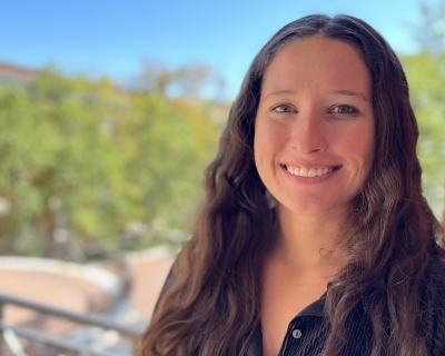 Head shot of young woman with long hair with campus in the background
