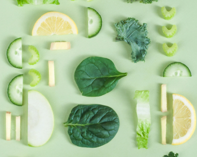 Photo of an array of sliced fresh produce: lemons, cucumbers, celery, kale, and spinach