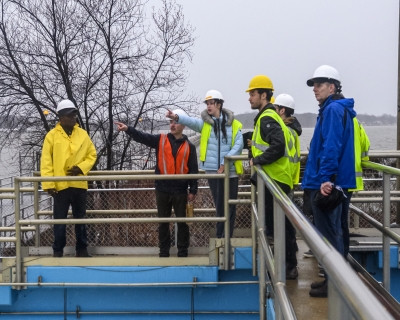 A group of people in rain gear standing on a platform. Two people are pointing.