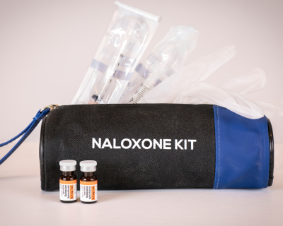 A bag labeled Naloxone Kit with syringes poking out of the top
