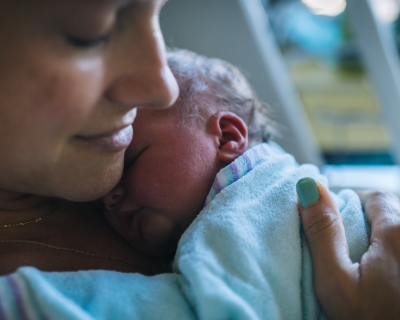 mother with newborn Closeup of mother holding newborn to her chest in hospital bed