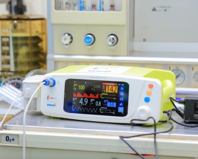 Image of a capnograph surgical monitoring device, a small whie box with a screen displaying vital statistics.
