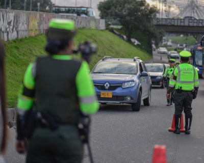 Police in Bogota wearing bright neon green safety shirts conduct speeding checks on a heavily trafficked road.
