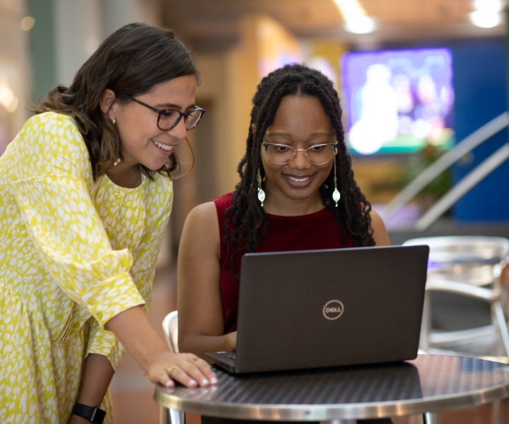 Two students look at a computer in the E. Monument Street entrance lobby of the BSPH building