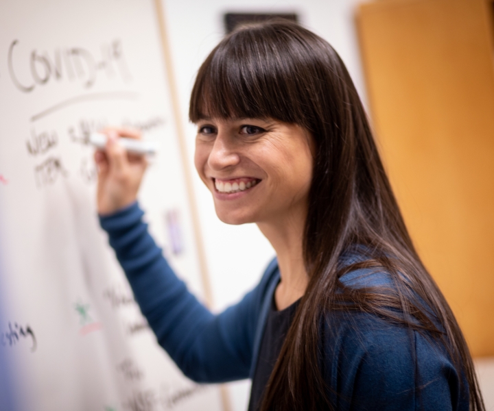 Young woman smiling and writing on a white board