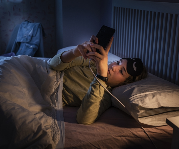Teenager laying in bed and using cell phone