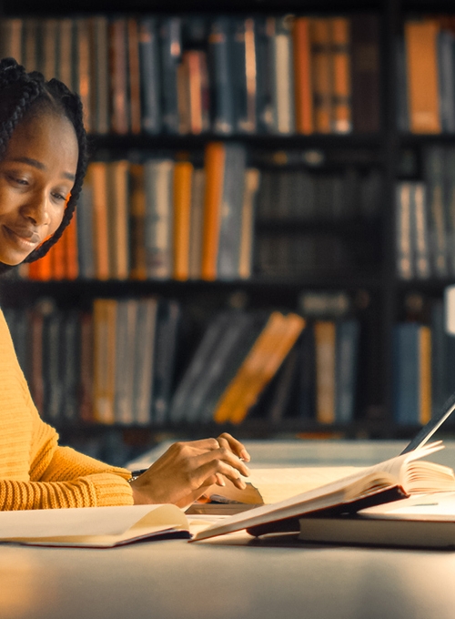 young woman reading book in a library