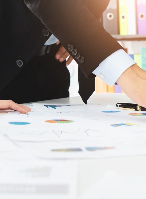 three people pointing to a computer and papers on a desk