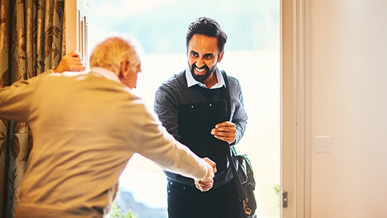 elderly man greeting a man at his door