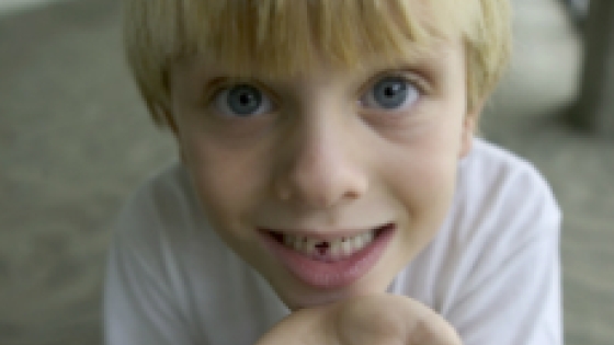 child holding a baby tooth