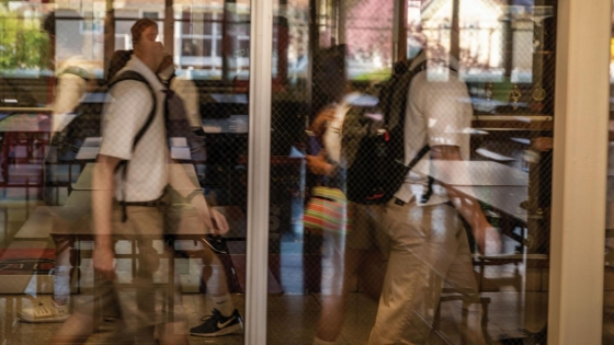 students walking past a glass enclosure in a cafeteria