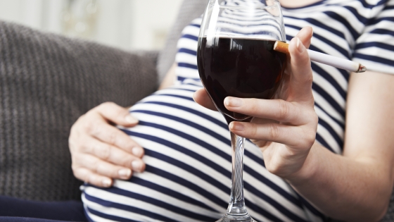 photo of pregnant women holding glass of wine