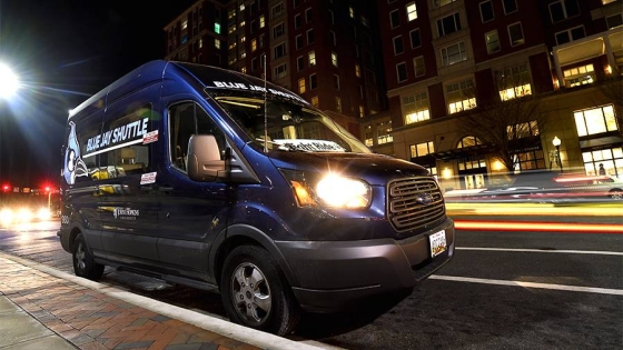 Blue Jay Shuttle operating at night as car lights blur in the background