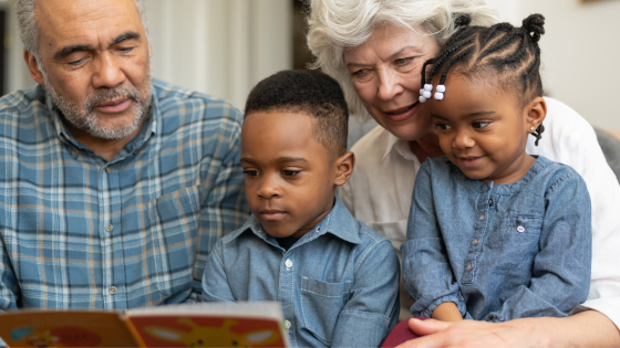 two adults and two kids reading a book