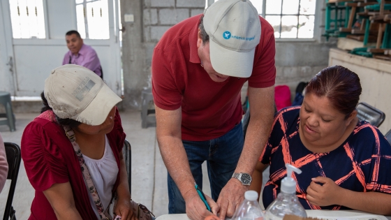 Vitamin Angels researcher working with two women at a distribution site in Mexico.