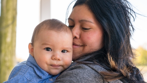 A mother holding her baby closely and kissing his head in the U.S.