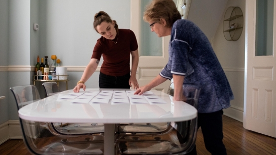 Photo of Amanda Mustard and her mother looking at a series of photographs on a table.