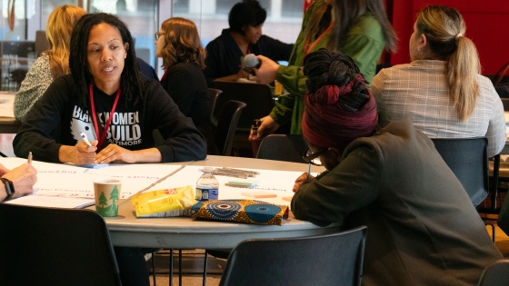 group of people gathered around a table talking and writing