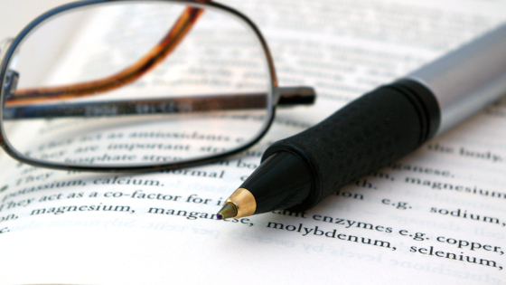 pair of glasses and pen on research paper