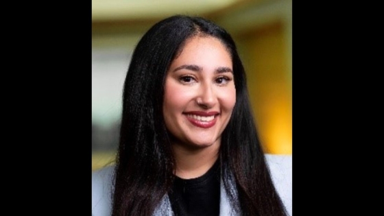 A headshot of a woman smiling as she wears a suit jacket