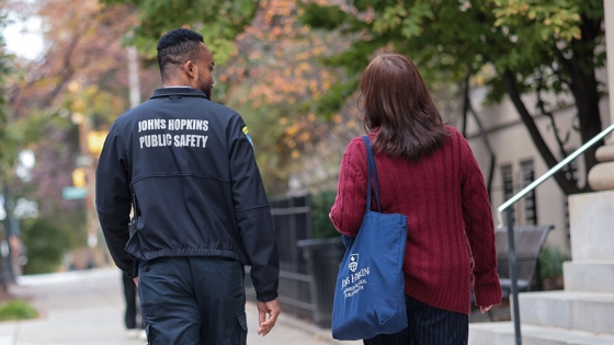 Public Safety Escort A Johns Hopkins public safety officer walks with a Johns Hopkins affiliate down a Baltimore street.