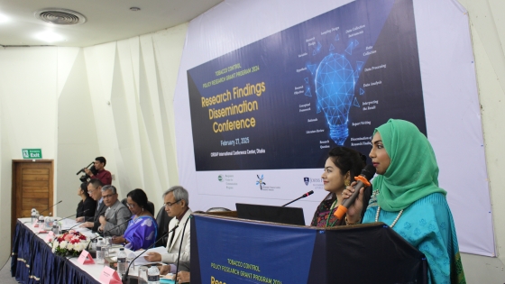 Two Bangladeshi women speak in front of a research conference