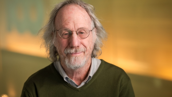 head shot of man in brown sweater and glasses
