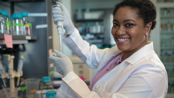 faculty-innovation-fund A woman in a lab with lab equipment in her hands smiling at the camera