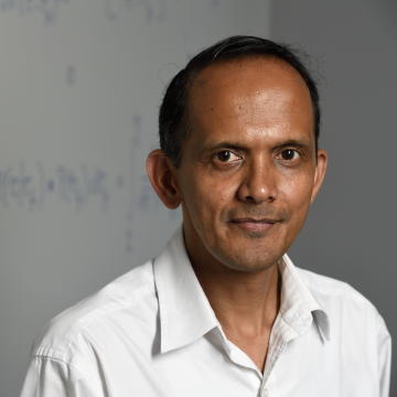 man smiling standing in front of chalkboard with mathematical equations