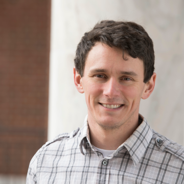man smiling standing in front of building 