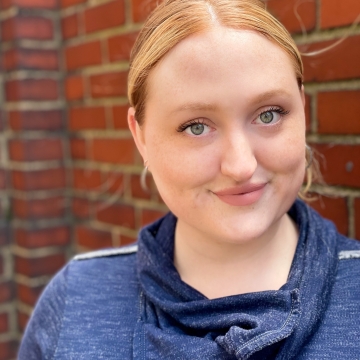 Professional headshot: woman stands smiling at camera