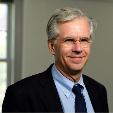 Headshot of HPM Distinguished Scholar Jeffrey Paul Michael wearing a suit jacket over a light blue button-up shirt with a black tie