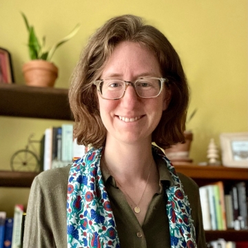 Headshot of HPM Assistant Scientist Michelle Duren wearing a light blue scarf with a pattern of various dark blue and purple shapes over a navy green blouse