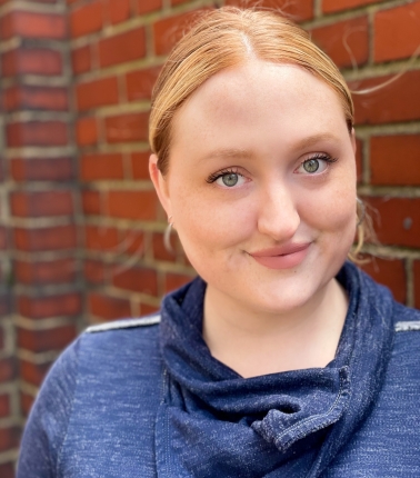 Professional headshot: woman stands smiling at camera