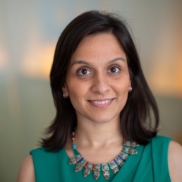 A portrait picture of a woman with black hair wearing silver jewellery and green attire.