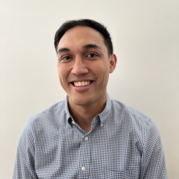 A headshot of Andrew Jopson wearing a button-down shirt