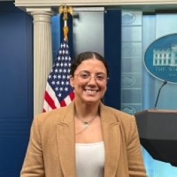 Woman wearing glasses standing in front of flag