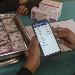 A person holding a phone over a tray with medical supplies