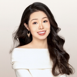 A headshot of a woman with an open mouth smile and long black hair