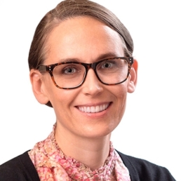 A headshot of Kate Miller, a woman with a light skin tone, dirty blonde hair tucked away into a ponytail, and dark glasses