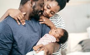 Two young parents hold their infant