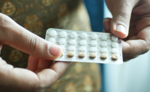 A person holding a packet of birth control pills