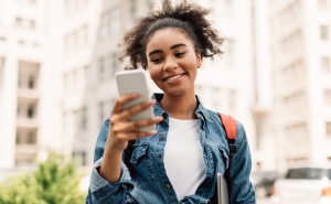 Teenager smiling while holding smartphone outside