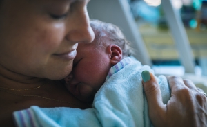 mother with newborn Closeup of mother holding newborn to her chest in hospital bed