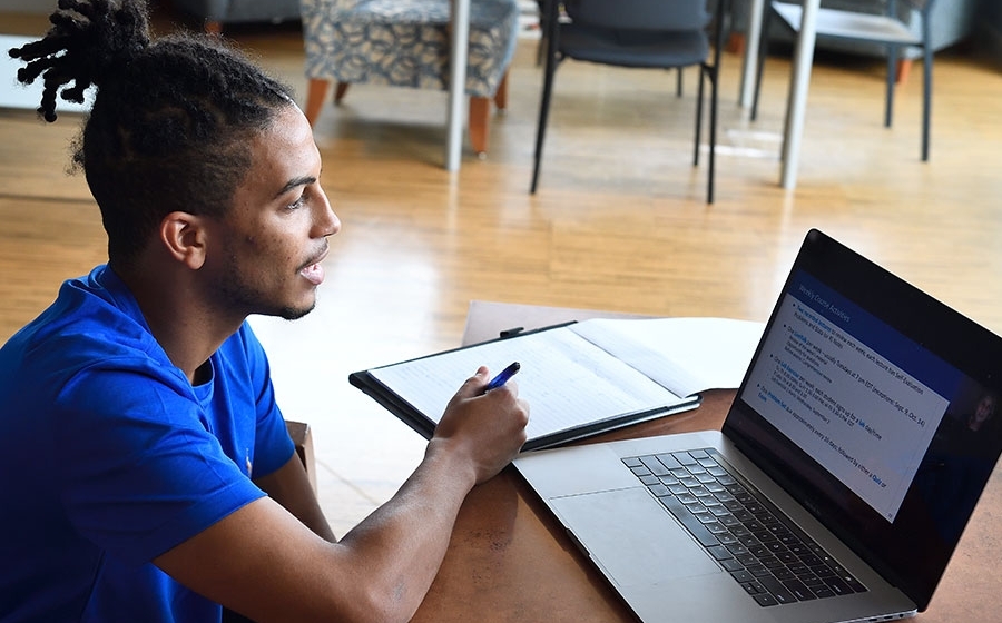 Student in blue shirt working on a laptop