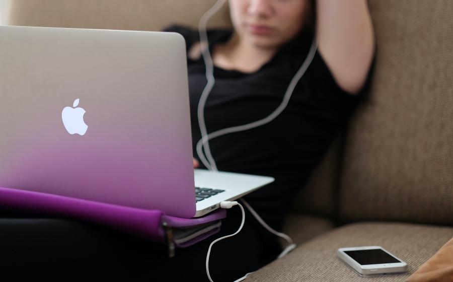 Student working on a laptop with earphones in
