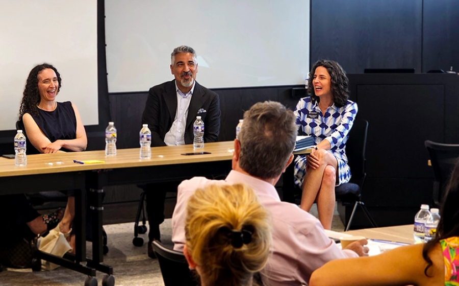 Two women and one man at a table laughing
